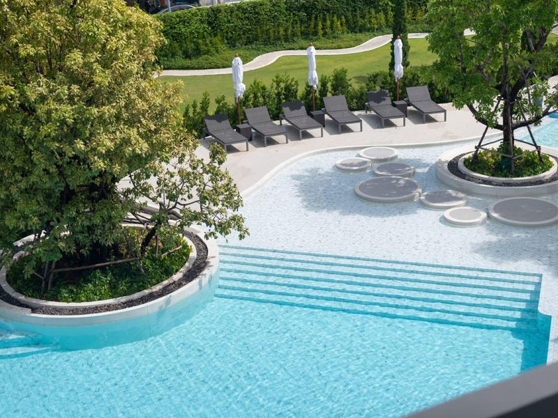 A serene pool area with built-in seating and outdoor lounge chairs.