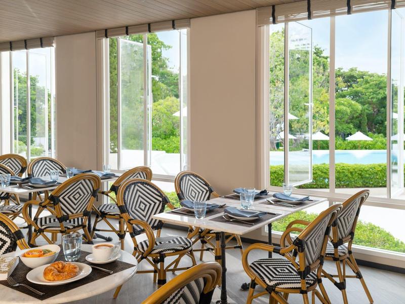 Bright restaurant with bistro chairs and view of terrace and garden.