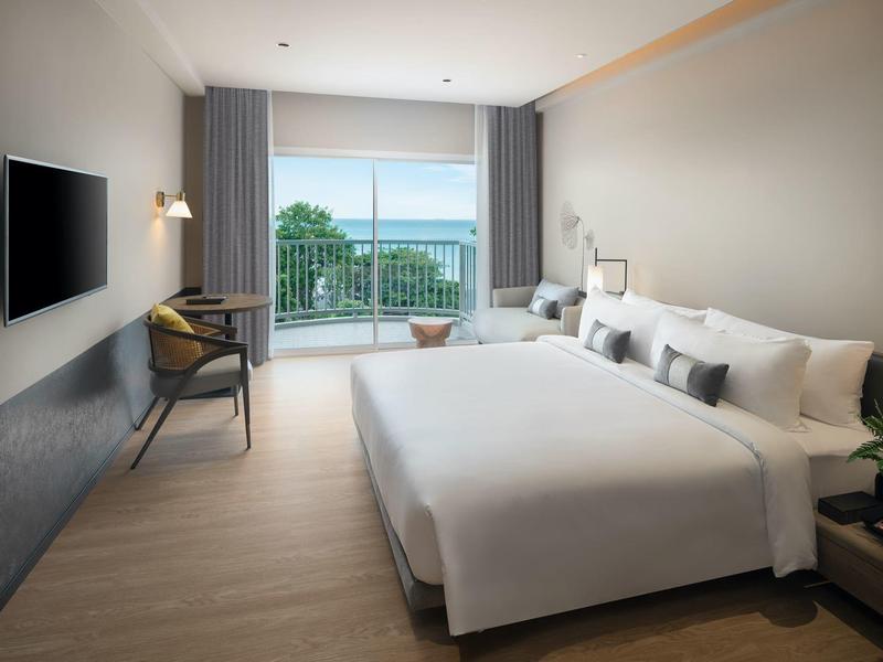 Modern hotel room with double bed and balcony overlooking the sea.