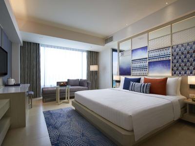 Camera d'hotel moderna con letto grande, scrivania, TV e decorazioni alle pareti.