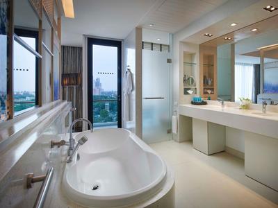 Bagno moderno con vasca autonoma, doppi lavandini e grandi finestre.