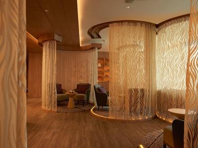 Area lounge con tende rotonde semitrasparenti e pavimento in legno caldo.