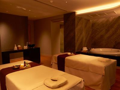 Area relax con due lettini da massaggio e una vasca idromassaggio in una stanza illuminata caldamente.