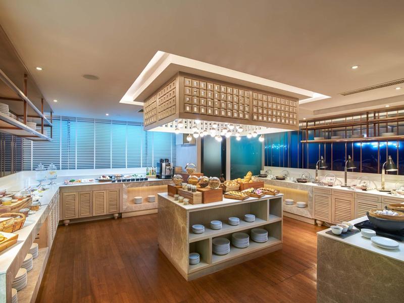 Area buffet elegante in hotel con pavimento in legno e illuminazione moderna.