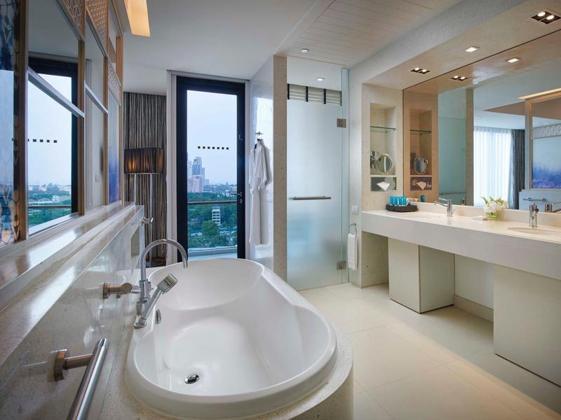 Bagno moderno con vasca autonoma, doppi lavandini e grandi finestre.