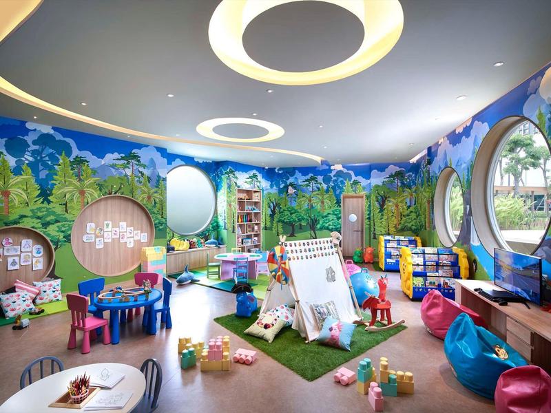 Sala giochi colorata per bambini con giocattoli, tavoli e finestre rotonde sulle pareti.