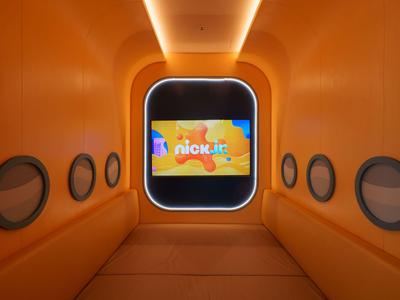 Moderner, orangefarbener Tunnel mit Fensteröffnungen und Bildschirm am Ende, Hotelambiente.