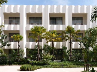 Moderne Hotelanlage mit weißen Fassaden und grünen Palmen im Vordergrund.