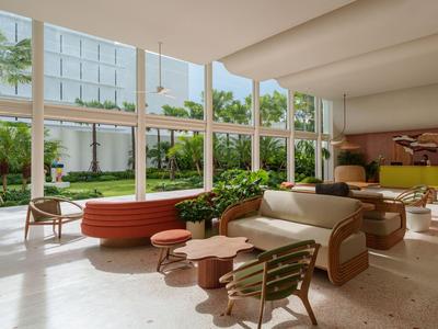 Modernes Hotel-Lounge mit großen Fenstern, bequemen Sitzgelegenheiten und Blick auf Garten.