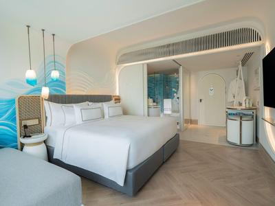 Modernes Hotelzimmer mit Doppelbett, Meerblick-Wanddekor und eleganten Beleuchtungskörpern.