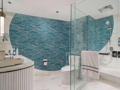 Modernes Badezimmer mit blauen Fliesen, Glasdusche und weißen Sanitäranlagen.