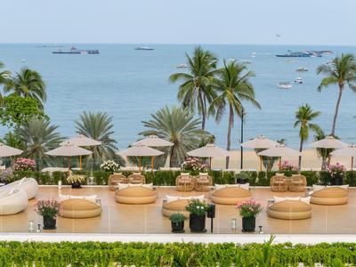 Luxuriöser Hotelpoolbereich mit Sonnenliegen, Palmen und Blick auf das blaue Meer.
