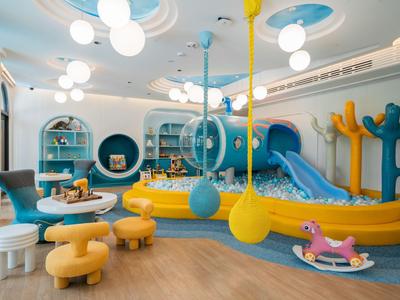 Helles, farbenfrohes Kinderspielzimmer mit Rutschen, Sitzecken und Spielzeug in einem Hotel.