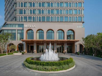 Modernes Hotelgebäude mit Brunnen und symmetrischem Eingangsbereich bei klarem Himmel.