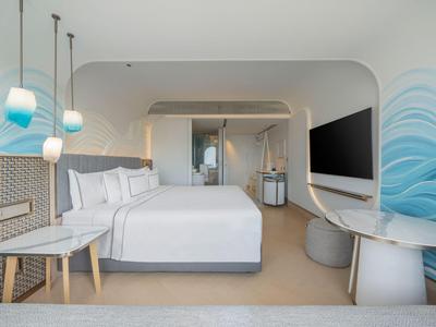 Modernes Hotelzimmer mit großem Bett, Schreibtisch, TV und stilvoller blauer Wandgestaltung.