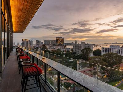 Moderner Balkon mit roten Stühlen und Glasgeländer bietet Blick auf Stadt bei Sonnenuntergang.