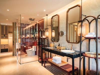 Modern hotel bathroom with double vanity and open shower area in warm lighting.