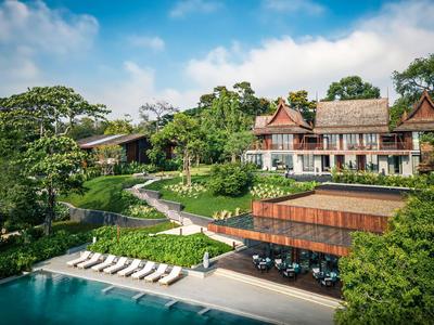Luxury hotel with pool, sun loungers, and lush tropical greenery.