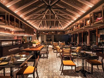Elegant restaurant with wooden ceilings, warm lighting, and modern chairs with orange cushions.