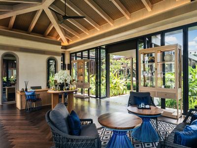 Bright hotel lounge area with large windows, wooden beam ceiling, and modern seating furniture.