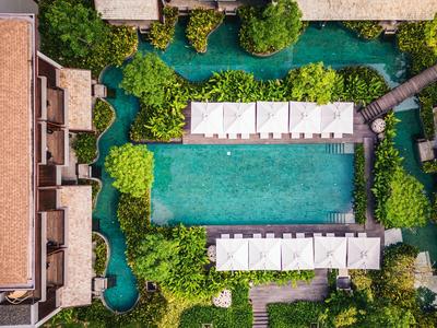 Outdoor pool with loungers in a green hotel garden with water canals.