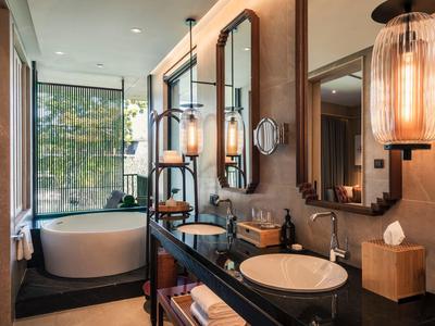 Luxurious bathroom with freestanding bathtub, large mirror, and modern lighting fixtures.