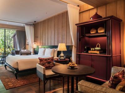 Cozy hotel room with double bed, wooden furniture, and large windows overlooking greenery.