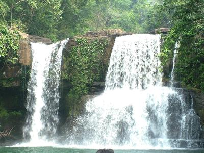 Doppia cascata circondata da folta vegetazione verde in un paesaggio naturale.