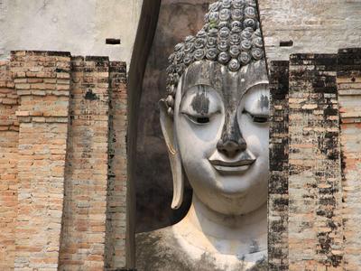 Large stone Buddha head nestled between aged brick walls in a historic temple.