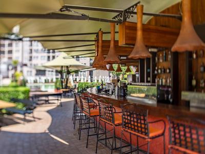 Außenbar mit Stühlen und Weingläsern unter einem schattigen Sonnendach