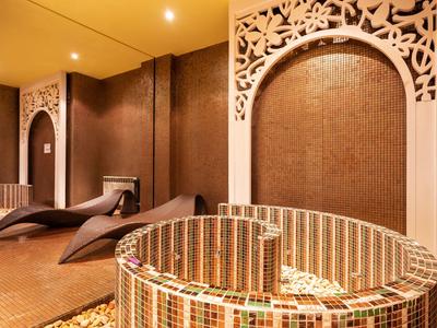 Entspannungsbereich mit geschwungenen Liegen und dekorativem Mosaik-Kamin in warmem Licht.