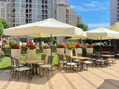 Freiluft-Terrasse mit Stühlen, Tischen und Sonnenschirmen in einer urbanen Umgebung.