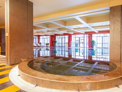 Großes, rundes Innenbecken mit warmem Wasser und gelben Wänden in einem Hotel