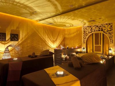 Gemütlicher Wellnessbereich mit gedämpftem Licht und zwei Massageliegen.