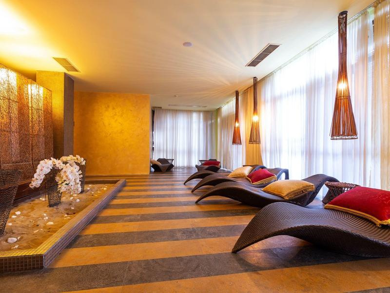 Entspannungsraum mit ergonomischen Liegen, warmem Licht und großen Fenstern.