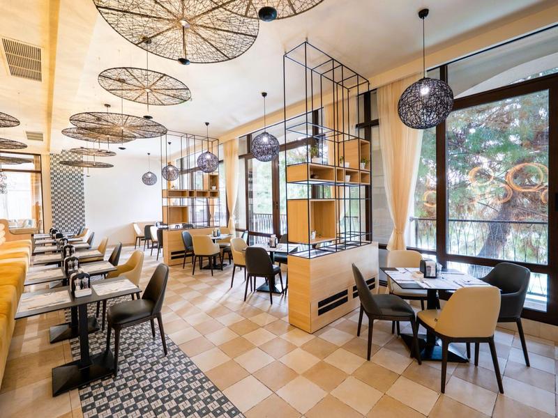 Helles, modernes Restaurant mit Holz- und Metallakzenten sowie großen Fenstern mit Blick nach draußen.