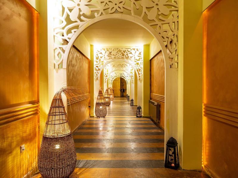 Flur mit dekorativem Gewölbebogen, warmes Licht und gemusterter Bodenbelag in einem Hotel.