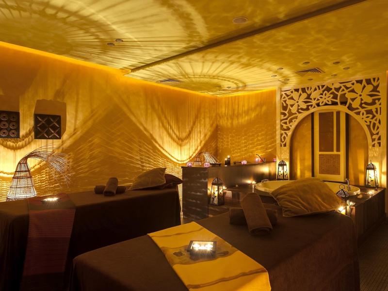 Gemütlicher Wellnessbereich mit gedämpftem Licht und zwei Massageliegen.