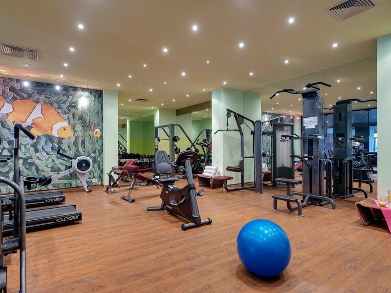 Heller Fitnessraum mit Trainingsgeräten und großem blauen Gymnastikball auf Holzfußboden.