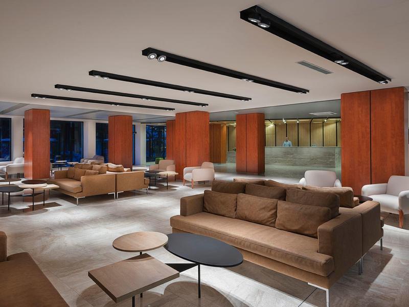 Moderní hotelová lounge s pohovkami a stolky v otevřeném, stylovém prostoru.