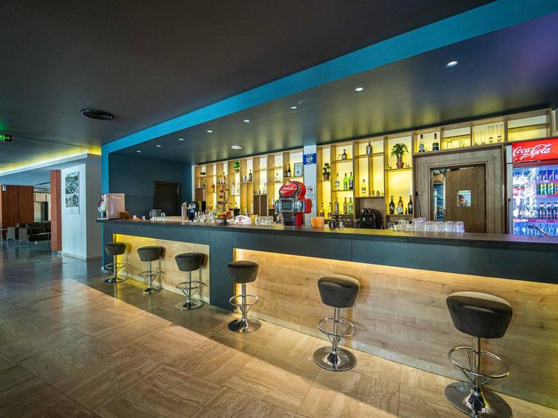 Moderní hotelový bar se osvětleným pultem a barovými židlemi v teplé atmosféře.