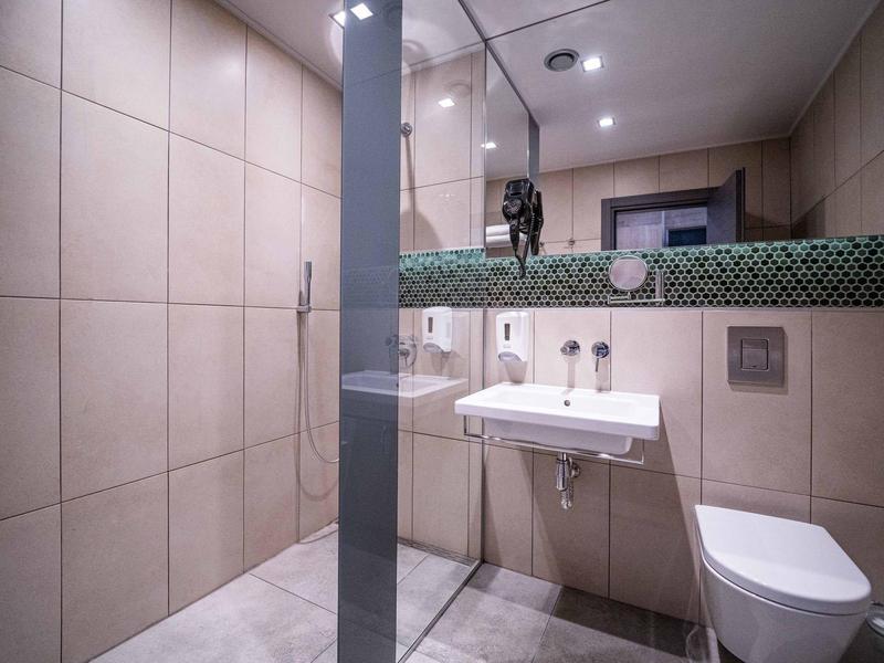 Moderní kompaktní koupelna s závěsným WC, umyvadlem a sprchovým koutem s skleněnou přepážkou.