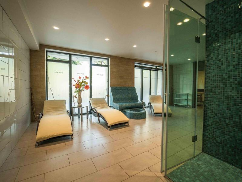 Moderní wellness prostor s lehátky a skleněnou sprchou v hotelu