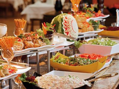 Buffet mit vielfältigen Speisen, frischen Salaten und dekorativem Melonenaufschnitt.