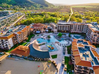 Großes Resort mit Pool, roten Dächern, grünen Bergen und offenem Tal im Hintergrund.