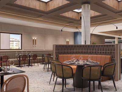 Restaurante moderno de hotel con mesas redondas, sillas e iluminación tenue.