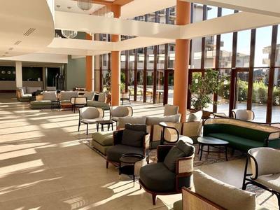 Heller Hotel-Loungebereich mit großen Fenstern, bequemen Stühlen und viel Tageslicht.