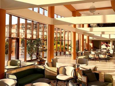Großer, heller Hotel-Lounge-Bereich mit modernen Sesseln und großen Fenstern.