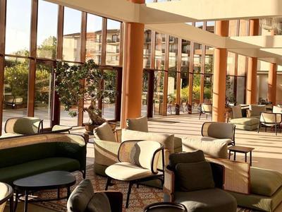 Heller Hotel-Loungebereich mit großen Fenstern und bequemen Sitzmöbeln.