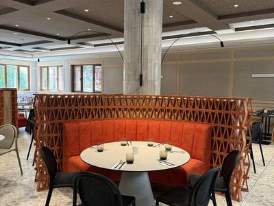 Moderner Hotel-Loungebereich mit rundem Tisch, schwarzen Stühlen und rotem Samtsofa vor einer Betonstütze.
